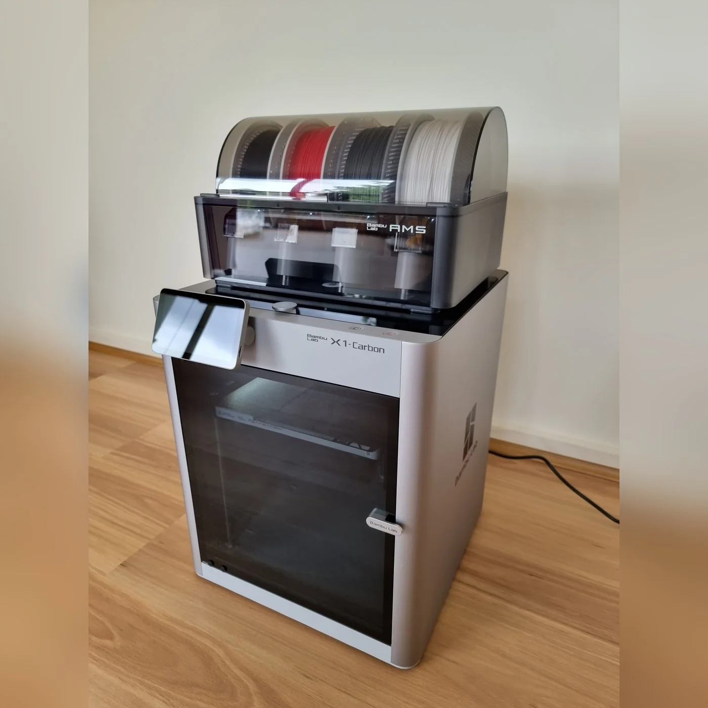 A Bambu Lab X1 Carbon filament printer with the AMS filament changer on top.